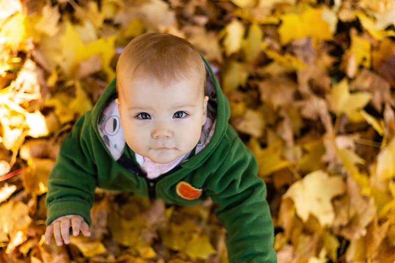 Daylight Saving Sleep for Baby: Young Baby Looking Up While Playing in Yellow Leaves